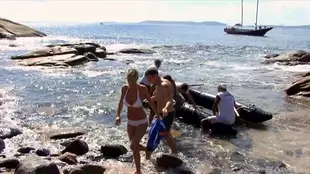 A group of men sexually assault a blonde woman in her swimwear at the beach