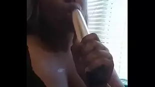 A busty Jamaican woman in her late twenties gives a satisfying blowjob to a large dildo